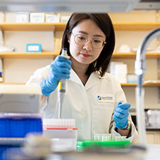 researcher in laboratory holding a pipette, conducting scientific experiment